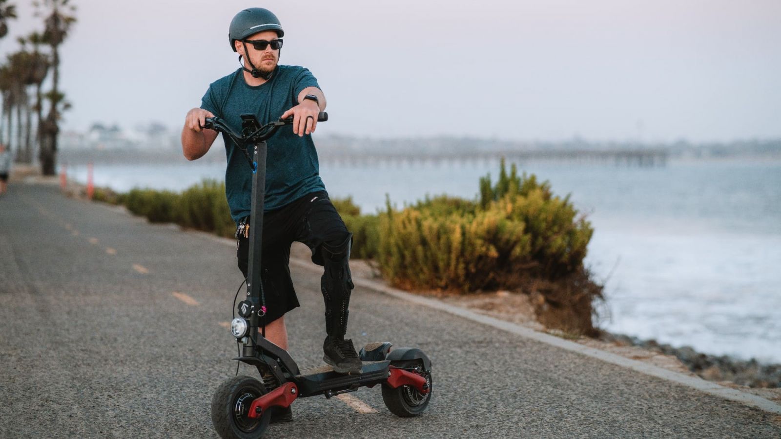 a person on an electric scooter with a protective helmet, on the background of the beach
