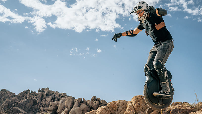 a person on an electric unicycle, monowheel, wearing a helmet, jumps